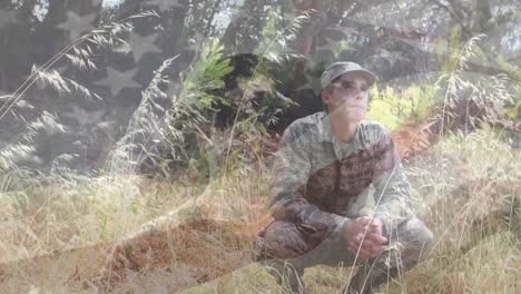 animation of flag of america, caucasian man standing, soldier sitting in squat position in forest