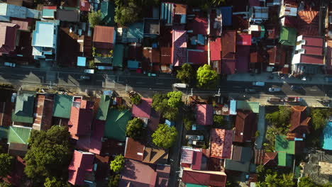 Birds-eye-aerial-above-cars-driving-in-middle-of-houses,-in-Luzon,-Philippines