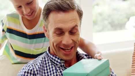 son giving his father a surprise gift in living room