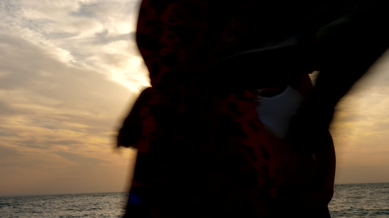 Silhouette of woman at the sea with a beautiful sceninc sunrise behind