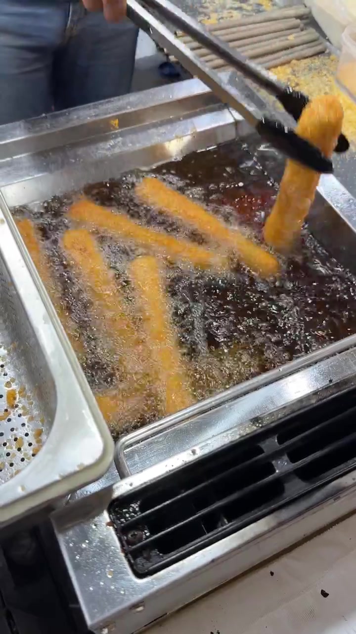 Kok fritterer sprøde churros i varm olie
