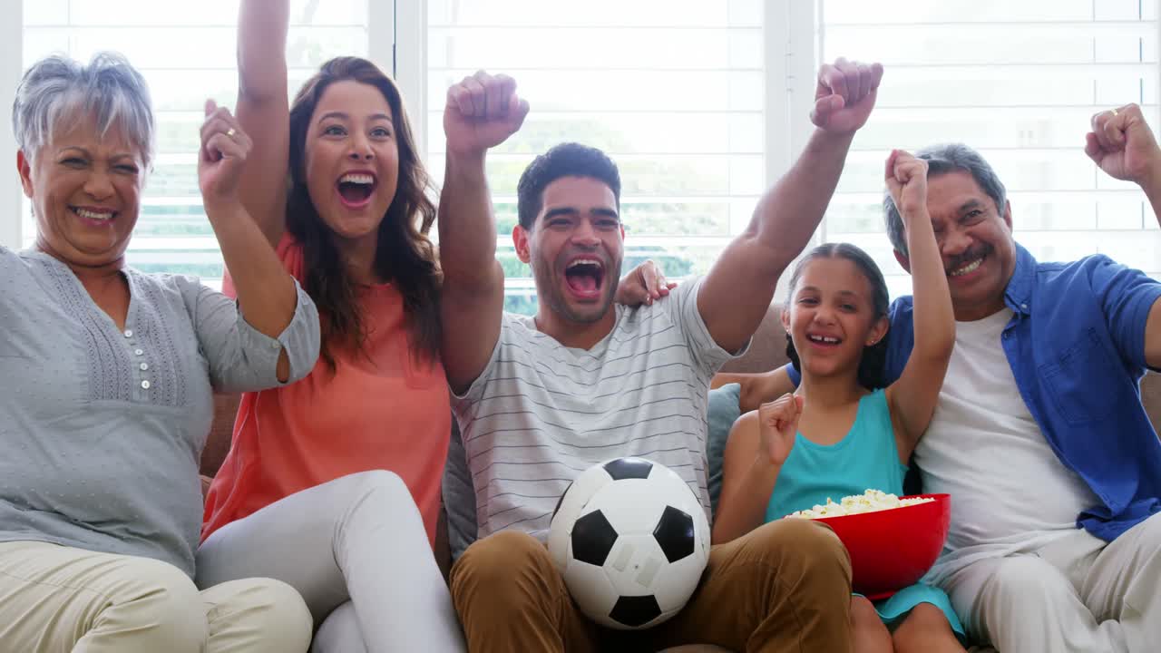 familia sentada en el sofá y viendo un partido de fútbol
