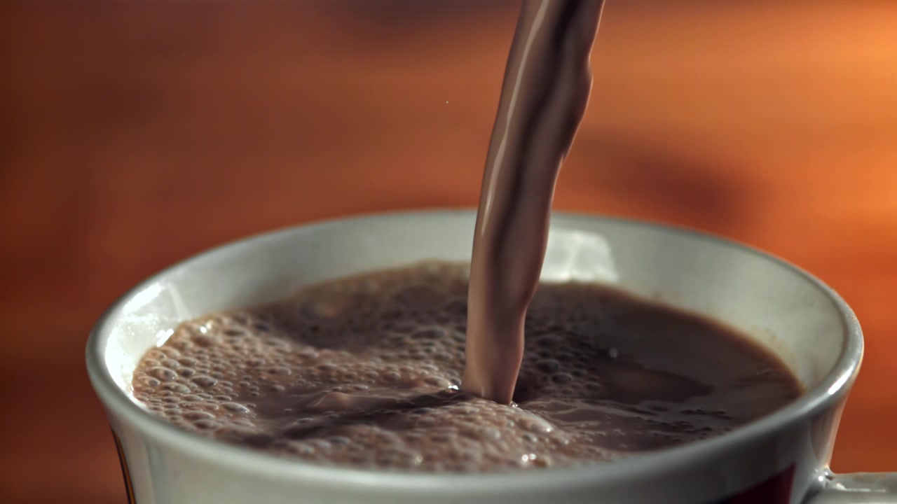 Latte al cioccolato versato in una tazza bianca, primo piano