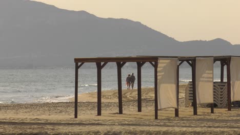 Two-Elderly-Women-Taking-Healthy-Walk-On-Sandy-Beach-At-Dawn