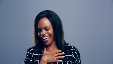 a-young-woman-laughing-against-a-grey-background