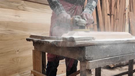 craftsman sanding and shaping wood with an angle grinder in a workshop