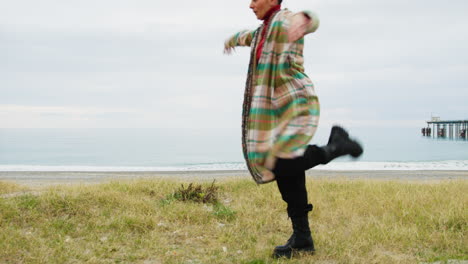 woman slowly dances on the beach near a dull mediterranean sea