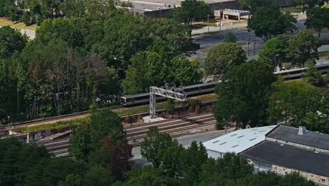 Aerial-zoom-shot-of-american-train-on-rail-in-Atlanta-City-reaching-train-station---Wide-shot-from-above