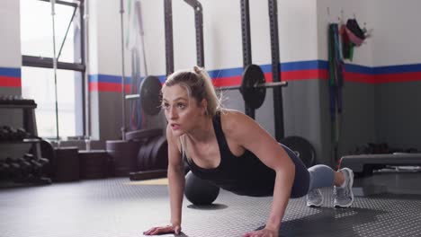 video of determined caucasian woman doing push ups working out at a gym