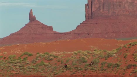 Long-Shot-Of-Cowboys-Riding-Through-Monument-Valley-Tribal-Park-In-Arizona