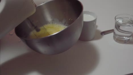 stirring pancake dough with hand held mixer in kitchen, cooking at home