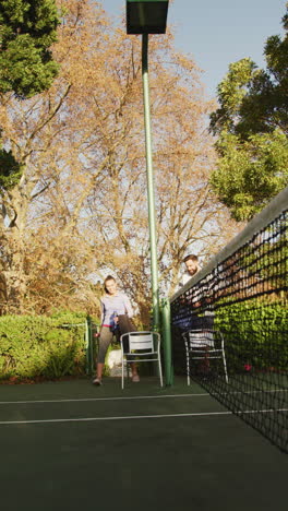 video vertical de una feliz pareja caucásica preparándose para jugar al tenis
