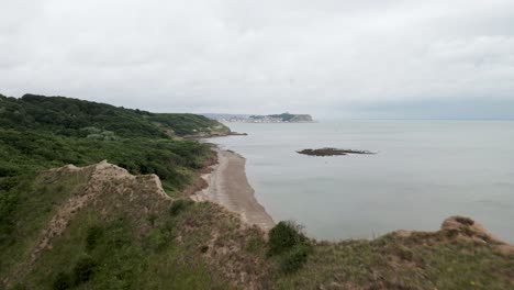 drone-shot-over-Cayton-bay-with-Scarborough,-North-Yorkshire-in-the-distance