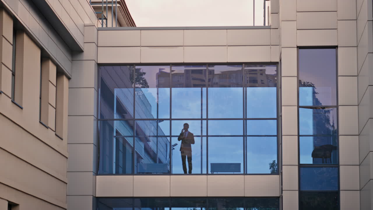 Silhouette businessman talking smartphone standing at window office building