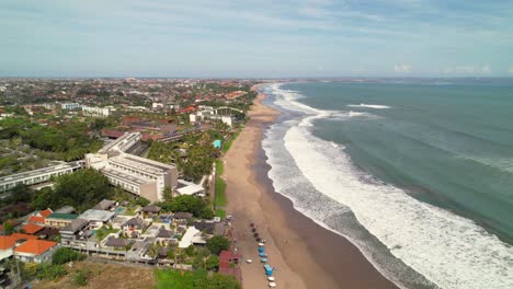 Long-Waves-Rolling-Over-Batu-Belig-Beach-Coastline-In-Berawa,-Bali-Indonesia---Aerial-Descending-Over-Coastline