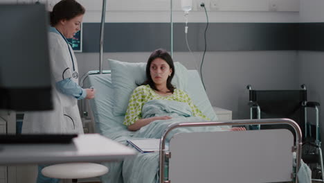 médico especialista chequeando a una mujer enferma hospitalizada que descansa en cama