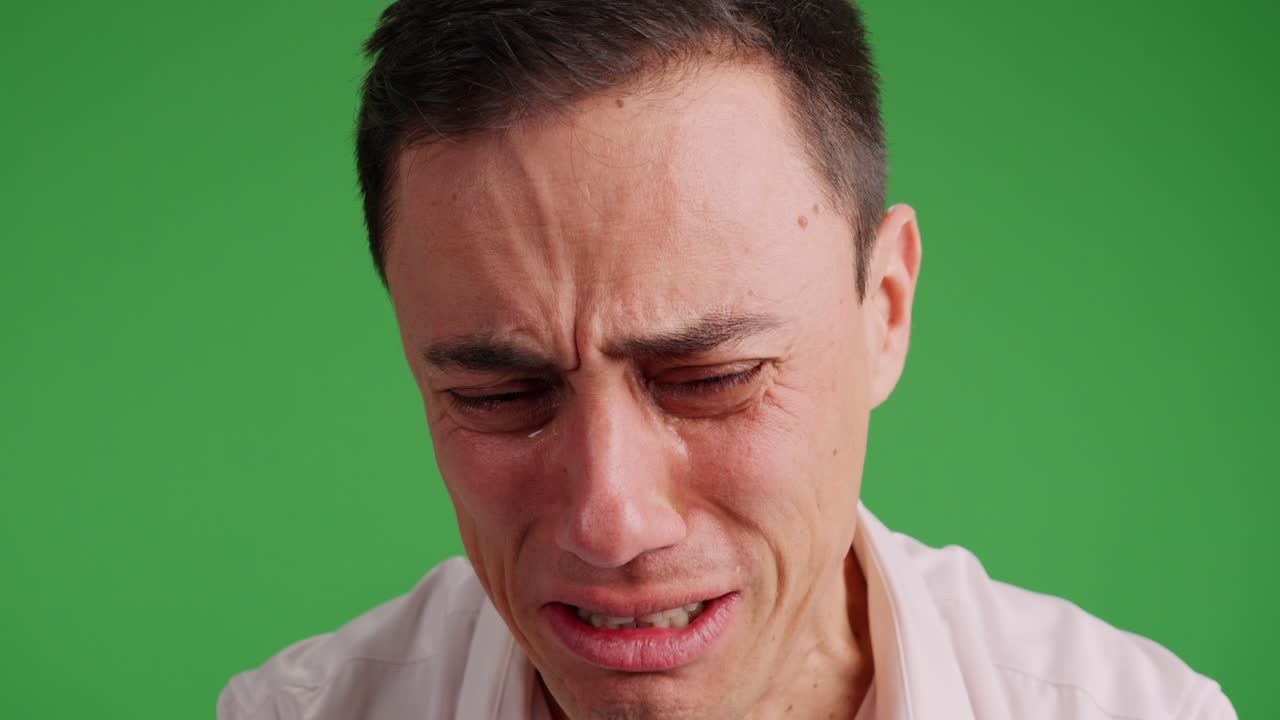 Sad man crying desperately on green screen background