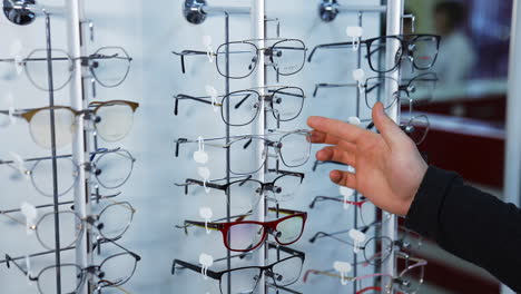 man choosing eyeglasses in optic store. handsome young man choosing eyeglasses frame in optical store