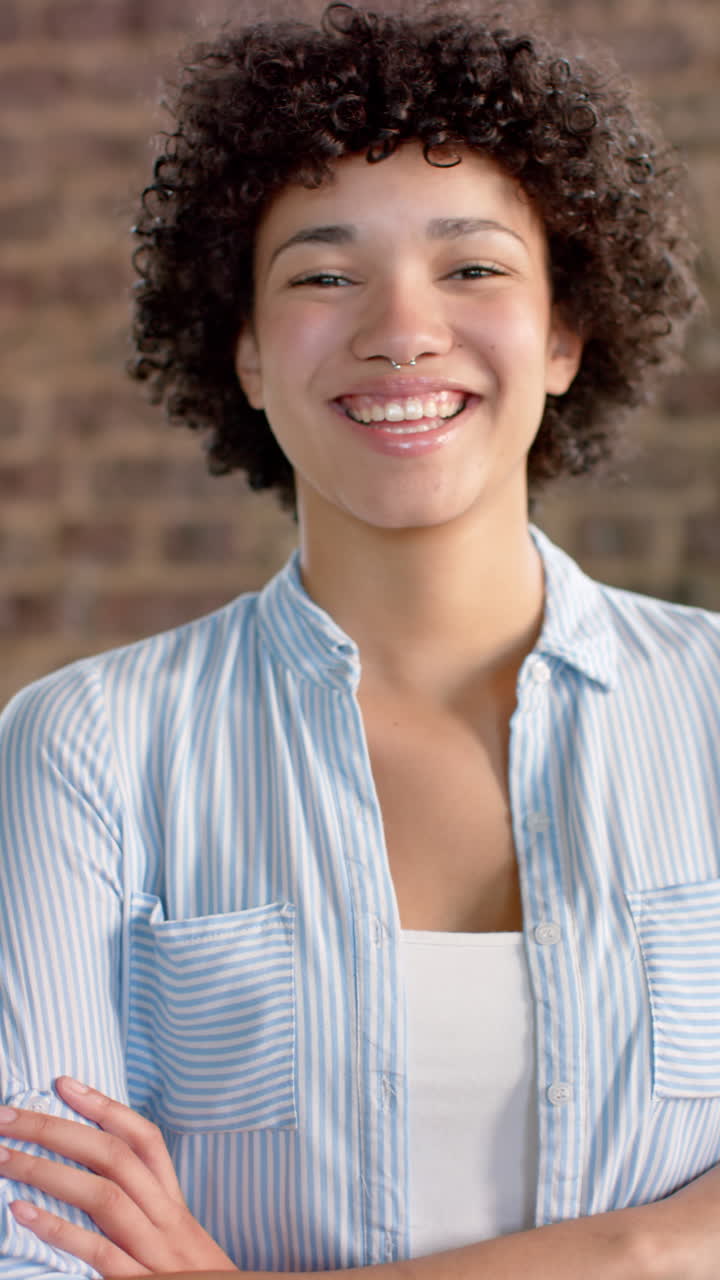 Vertical video of portrait of happy biracial casual businesswoman in office in slow motion