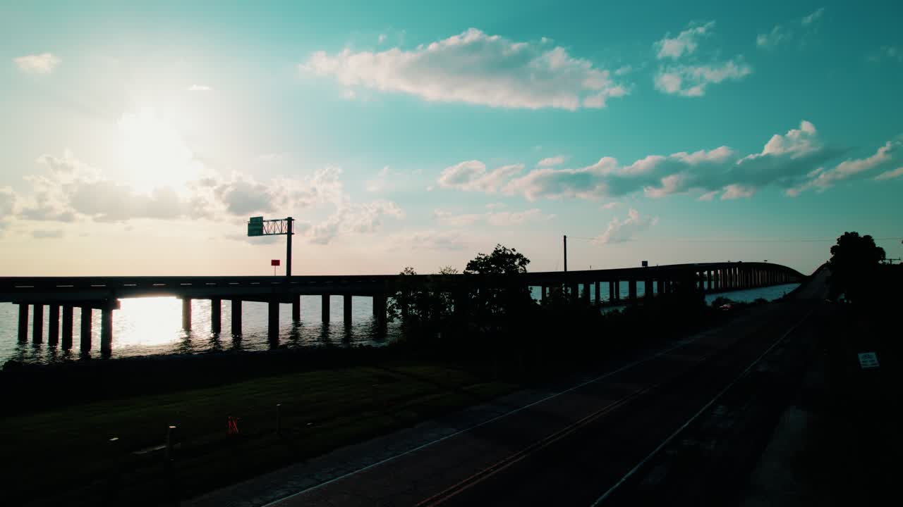Sunset view of the Manchac Swamp Bridge with glowing reflections on water, highway perspective, and a dramatic Southern sky.