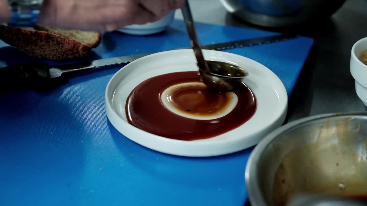 Chef applies melted caramel to a plate with a ladle before serving