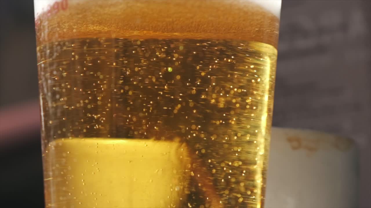 un vaso de cerveza radiante en cámara lenta en el mostrador de un bar soleado
