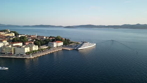 Wunderschönes-Rundpanorama-Aus-Der-Luft-über-Die-Altstadt-Von-Zadar-Und-Das-Angedockte-Luxuskreuzfahrtschiff,-Während-Das-Motorboot-Auf-Die-Offene-Adria-Hinausrast