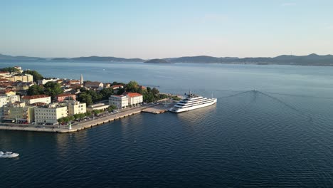 Hermoso-Panorama-Circular-Aéreo-Sobre-El-Casco-Antiguo-De-Zadar-Y-El-Crucero-De-Lujo-Atracado-Mientras-La-Lancha-Motora-Se-Apresura-Hacia-El-Mar-Abierto