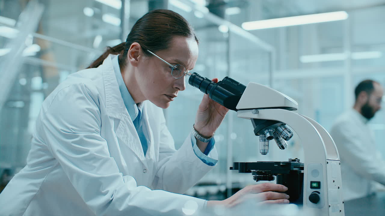 Female Scientist Adjusting Microscope while Conducting Laboratory Research