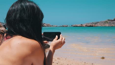 una mujer jugando con su teléfono inteligente en la playa