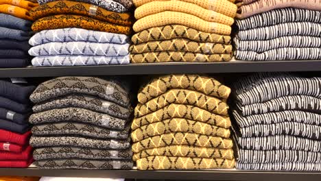 stack of folded sweaters in a clothing store