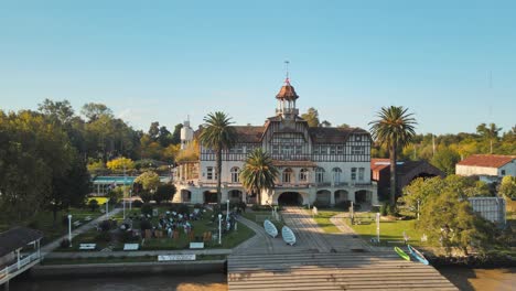 Aerial-orbit-of-Tigre-private-rowing-club-near-de-la-Plata-river-surrounded-by-vegetation-at-golden-hour,-Buenos-Aires