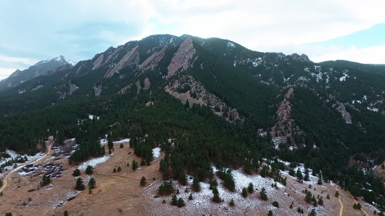 Close up aerial of Boulder Flatirons’ towering rock formations with forested base and clear skies