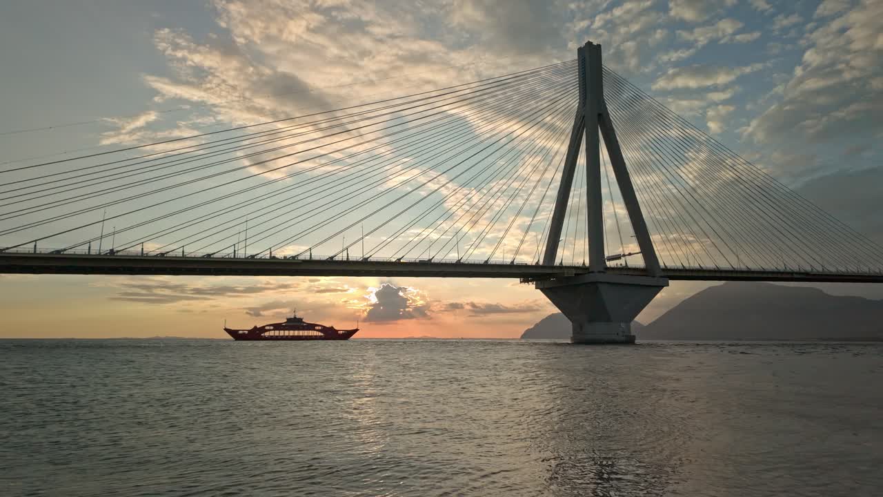 Sunset view of a cable-stayed bridge and a ferry at sea