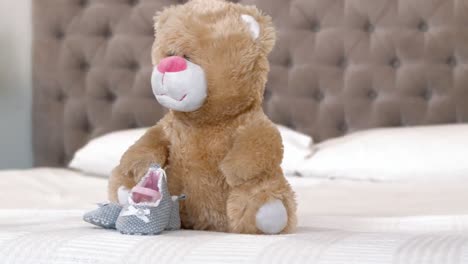 baby shoes and teddy bear on bed