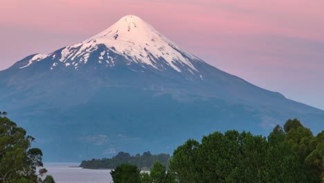 Aerial-tranquil-scene-featuring-a-snow-covered-Osorno-Volcano-peak-bathed-in-the-warm-hues-of-a-sunset-sky