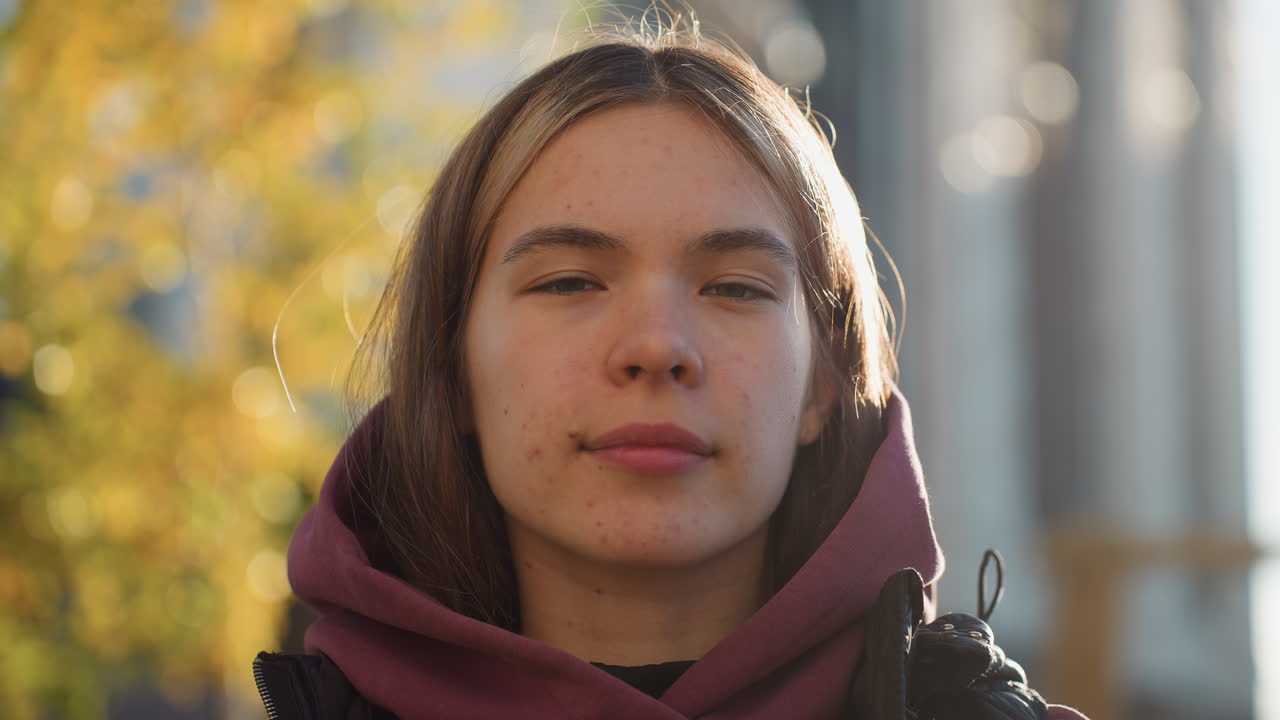 Portrait of female athlete removing hood in outdoor urban park workout session, confident smile and focused gaze shining through hoodie under morning sun, casual vest highlighting sporty lifestyle