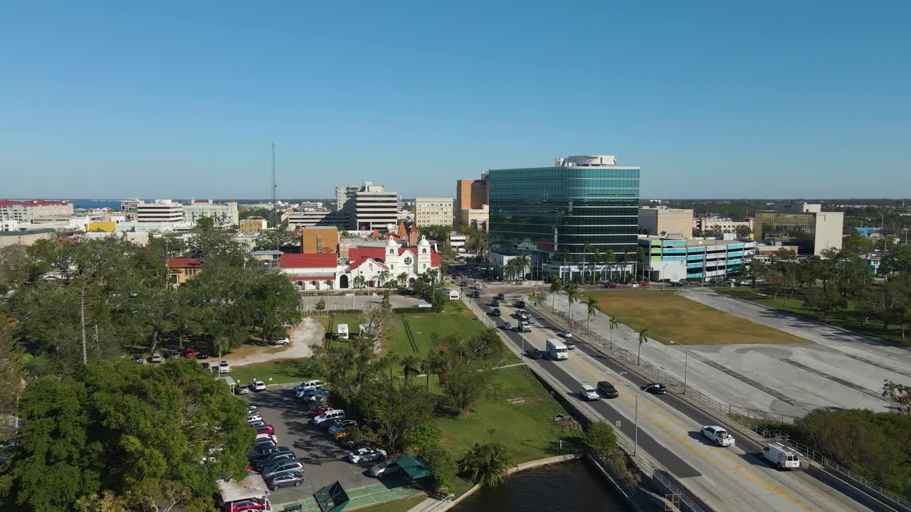 Aerial drone view of downtown Bradenton Florida showcasing buildings, and surrounding cityscape under clear blue skies. Dolly Backward E