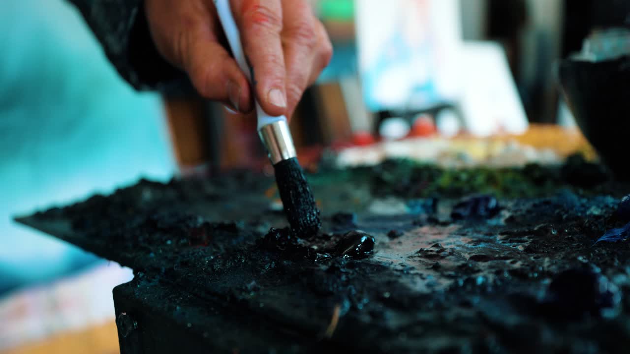Artist Painter getting the black paint from his palette to his brush to start painting
