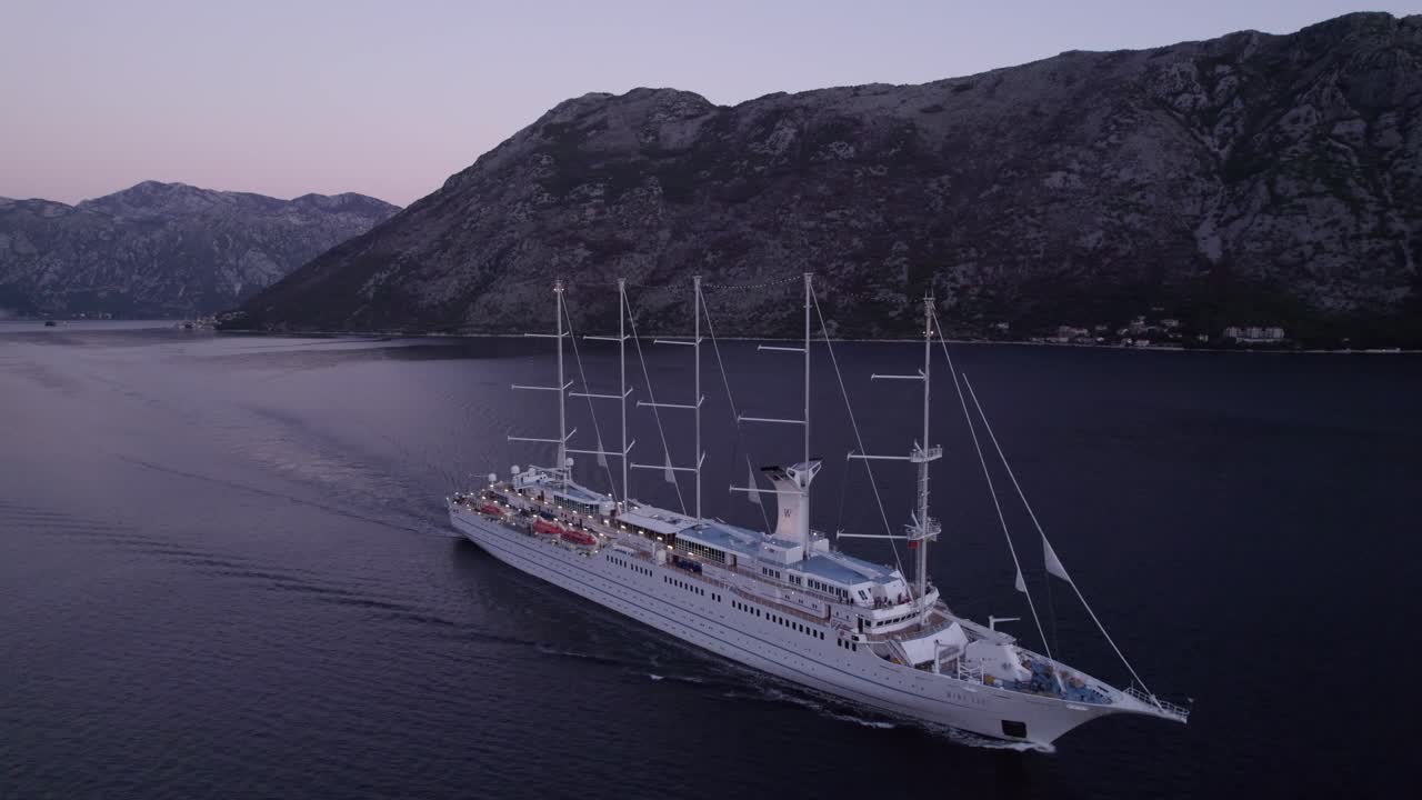 Ilmakuva MSY Wind Surf -aluksesta Kotorinlahdella auringonnousun aikaan Kotorissa, Montenegrossa, upeassa auringonnousun valossa, rauhallisessa tunnelmassa, korkealaatuista dronekuvamateriaalia, joka tallentaa seesteisiä hetkiä