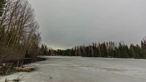 time lapse looking down a frozen river in a thick forest towards the setting sun