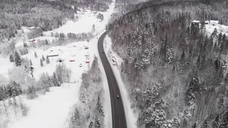 narrow highway road across white snow covered landscape in norway - aerials shot