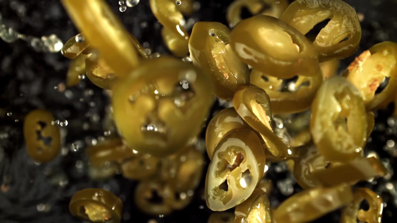 Fette di jalapeño sottaceto che schizzano nell'acqua al rallentatore