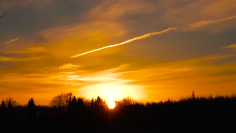 Épico-Cielo-Saturado-De-Puesta-De-Sol-De-Hora-Dorada-Con-Silueta-De-Bosque-Y-Estela-De-Avión