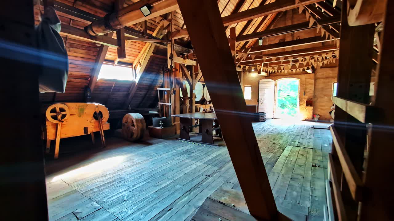 Interior of an old wooden building featuring exposed beams, rustic timber, and antique machinery in Jaunpils, Latvia