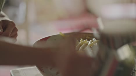 chef vertiendo aceite de oliva sobre frijoles de cera amarilla recién hervidos