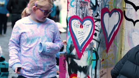 artists painting heart graffiti on a wall