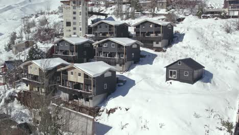 Aerial-view-dolly-in-close-proximity-to-black-cabins-nearing-completion-for-lodging-in-the-mountain-village-of-Farellones,-Chile