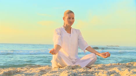 woman in white doing yoga on the beach