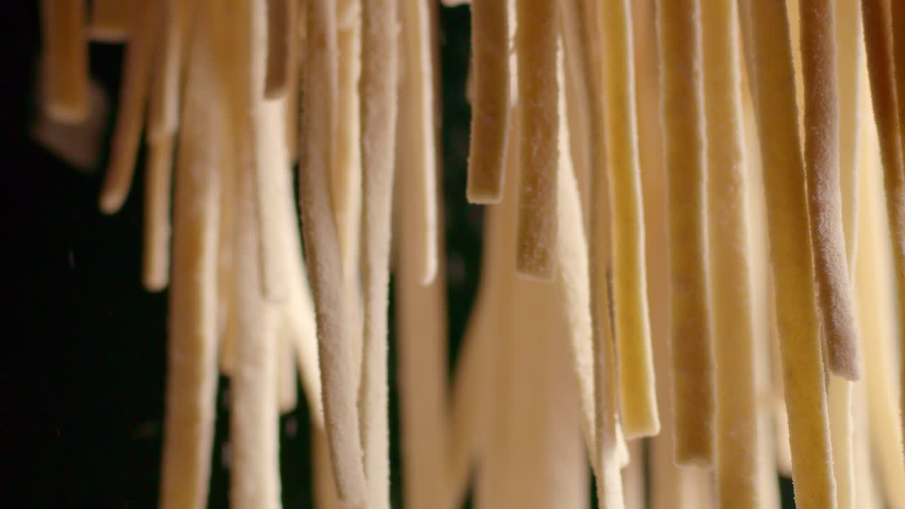 la harina está siendo arrojada sobre los fideos de pasta mientras cuelgan en el aire